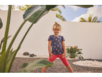 Menina com t-shirt de morangos e leggings capri vermelhas Lupilu.
