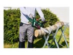 Person cutting a log with a cordless chainsaw on a sawhorse in a garden.