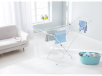 A white Brabantia laundry airer stands in a bright room, holding freshly washed clothes.