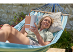 Woman relaxing in a Livarno Hammock with Frame, reading a book outdoors.