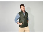 Homem sorridente com colete acolchoado verde Livergy e calças bege.
