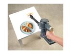 Handheld vacuum cleaning croissant crumbs from a white table next to a plate of croissants.