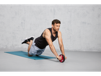 Man using a Crivit ab roller on a blue fitness mat.