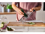 Pessoa a ralar curgete com um ralador multifuncional SILVERCREST numa cozinha.