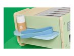 Wooden toy toaster with a salt shaker and blue tongs on a green background.