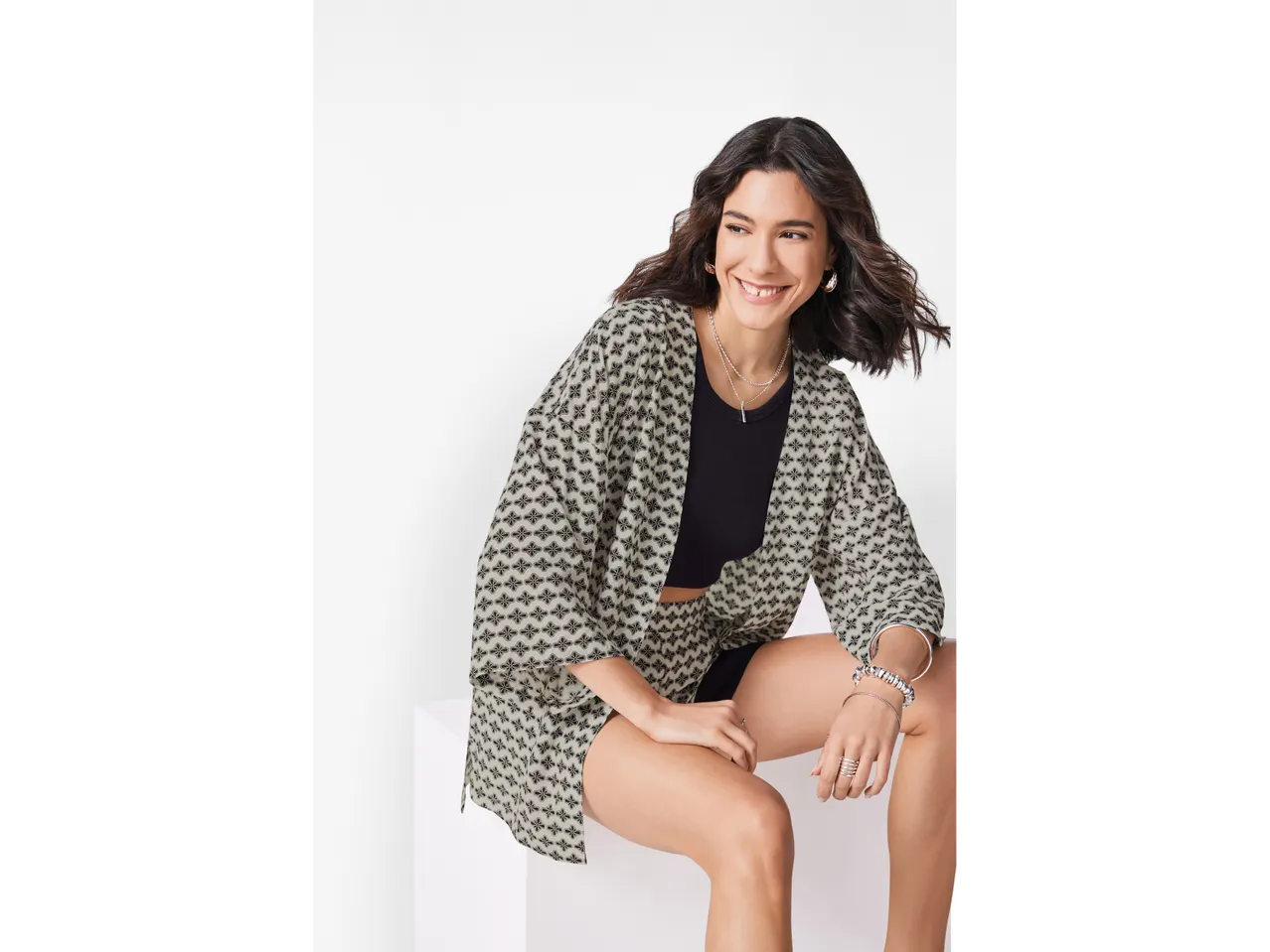 Donna sorridente indossa un kimono a stampa floreale e pantaloncini coordinati.