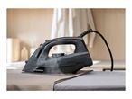 Black steam iron on an ironing board, with steam rising from the soleplate.