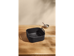 Black air fryer basket on a wooden table with a small bowl of salt