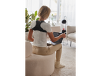 Woman using laptop with back support at home.