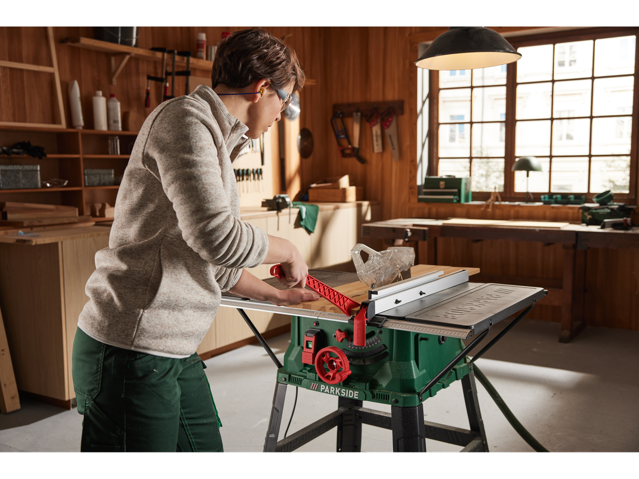 A woman uses a Parkside table saw in a workshop.
