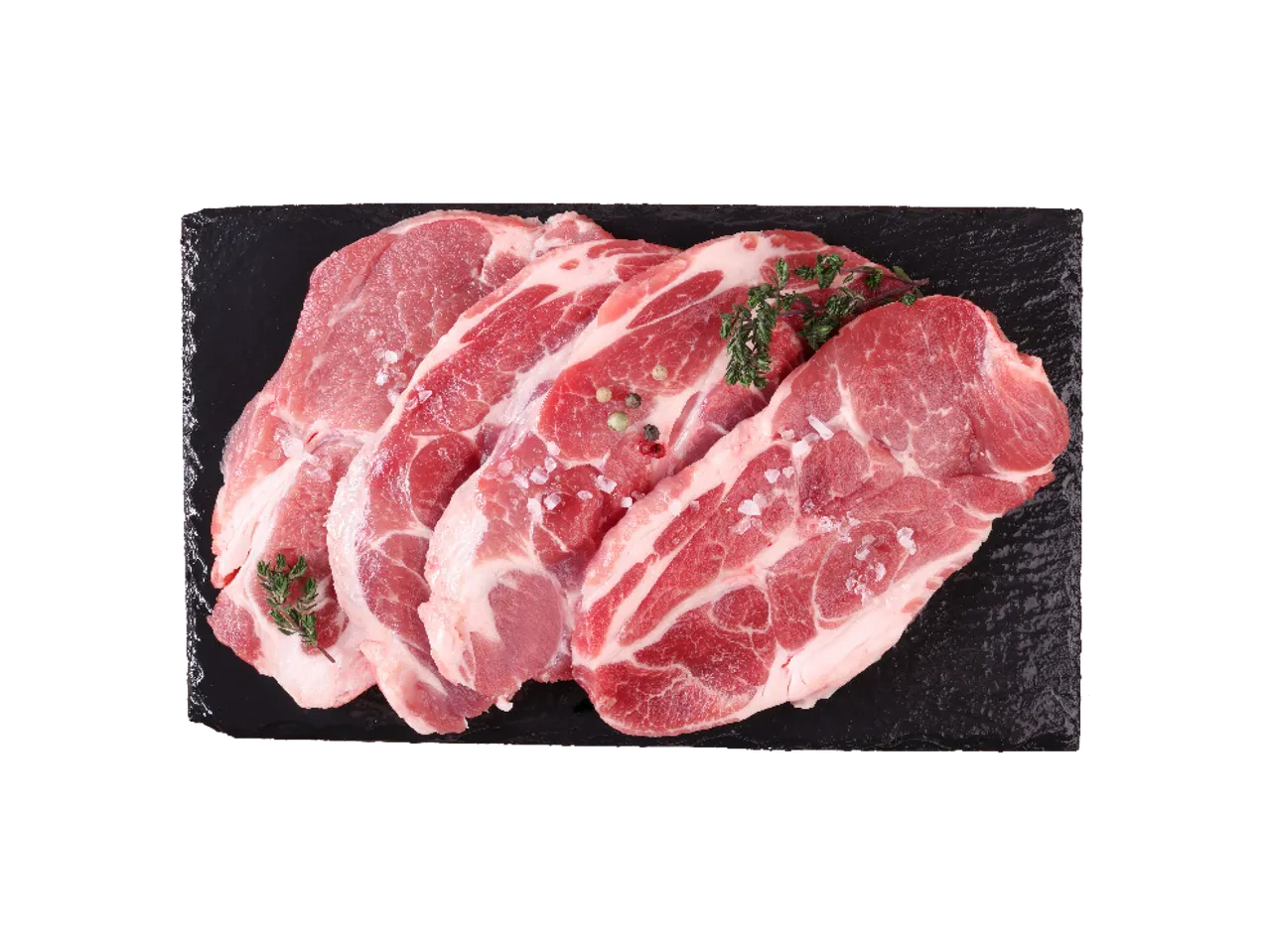 Sveži svinjski vrat sa začinima na crnoj ploči.