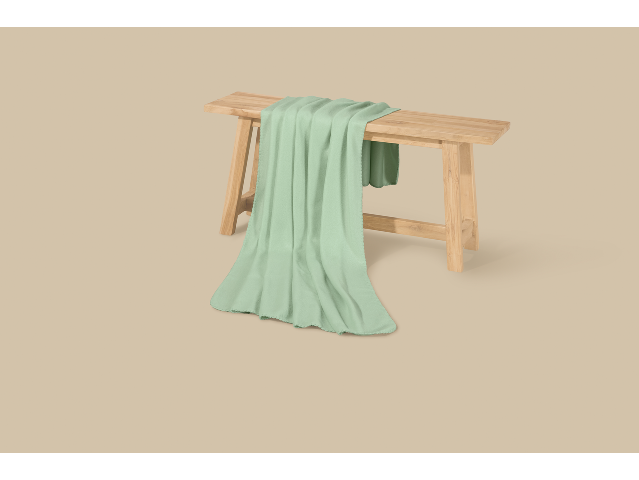 Мента зелено ћебе на дрвеној клупи, на беж позадини.