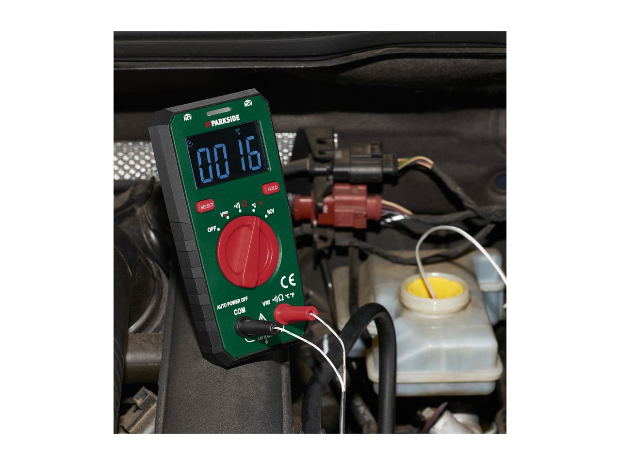 Digital multimeter displaying '0016 °C' measuring temperature in a car engine.