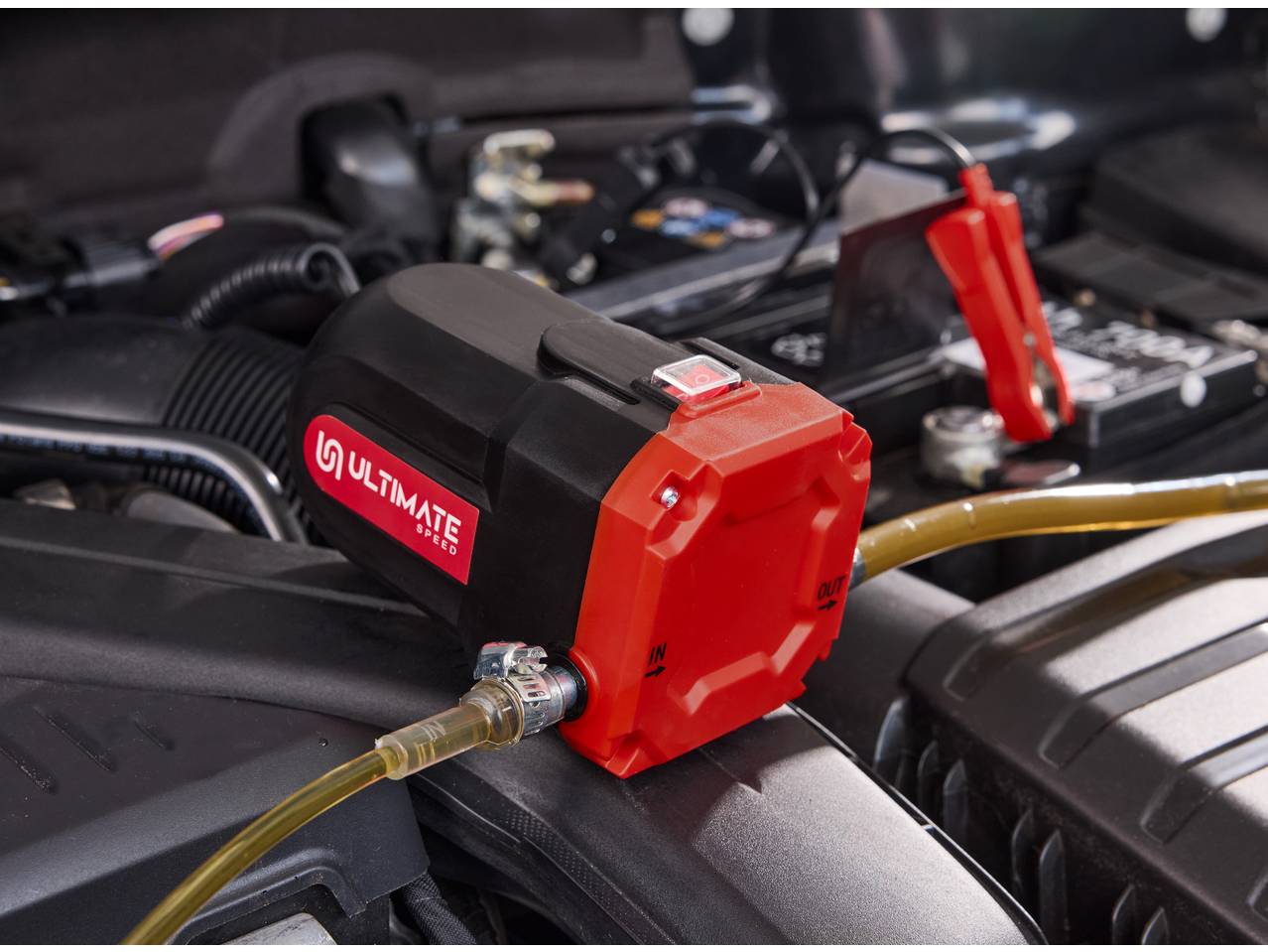 ULTIMATE SPEED® 12V Oil Pump connected to a car battery in an engine bay.