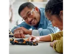 A girl and her father play with a LEGO McLaren Formula 1 race car.