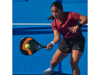 Mulher a jogar padel com uma raquete e bola num campo azul.