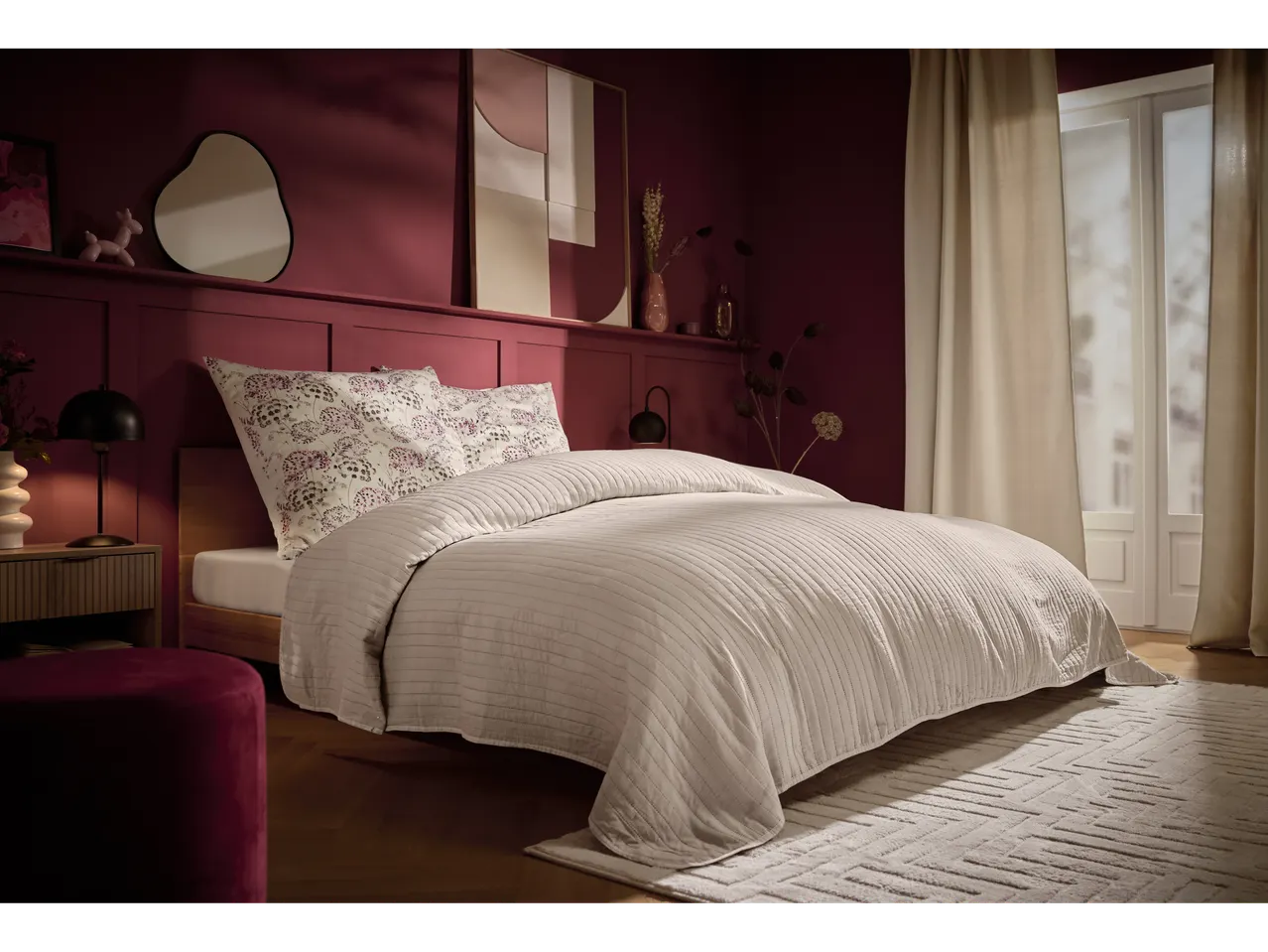 Dormitor cu pereți vișinii, pat cu așternuturi albe și covor pufos Livarno Home.