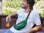 Man in a white t-shirt and black bucket hat, wearing a green Parkside fanny pack.