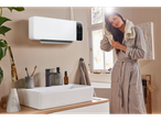 Femme séchant ses cheveux dans une salle de bain avec un chauffage mural céramique Silvercrest®.