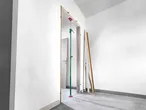 A green and red Ceiling Support Rod holds a door frame in place during installation.