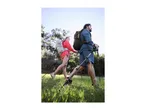 Two hikers with backpacks and trekking poles walking through a grassy area.