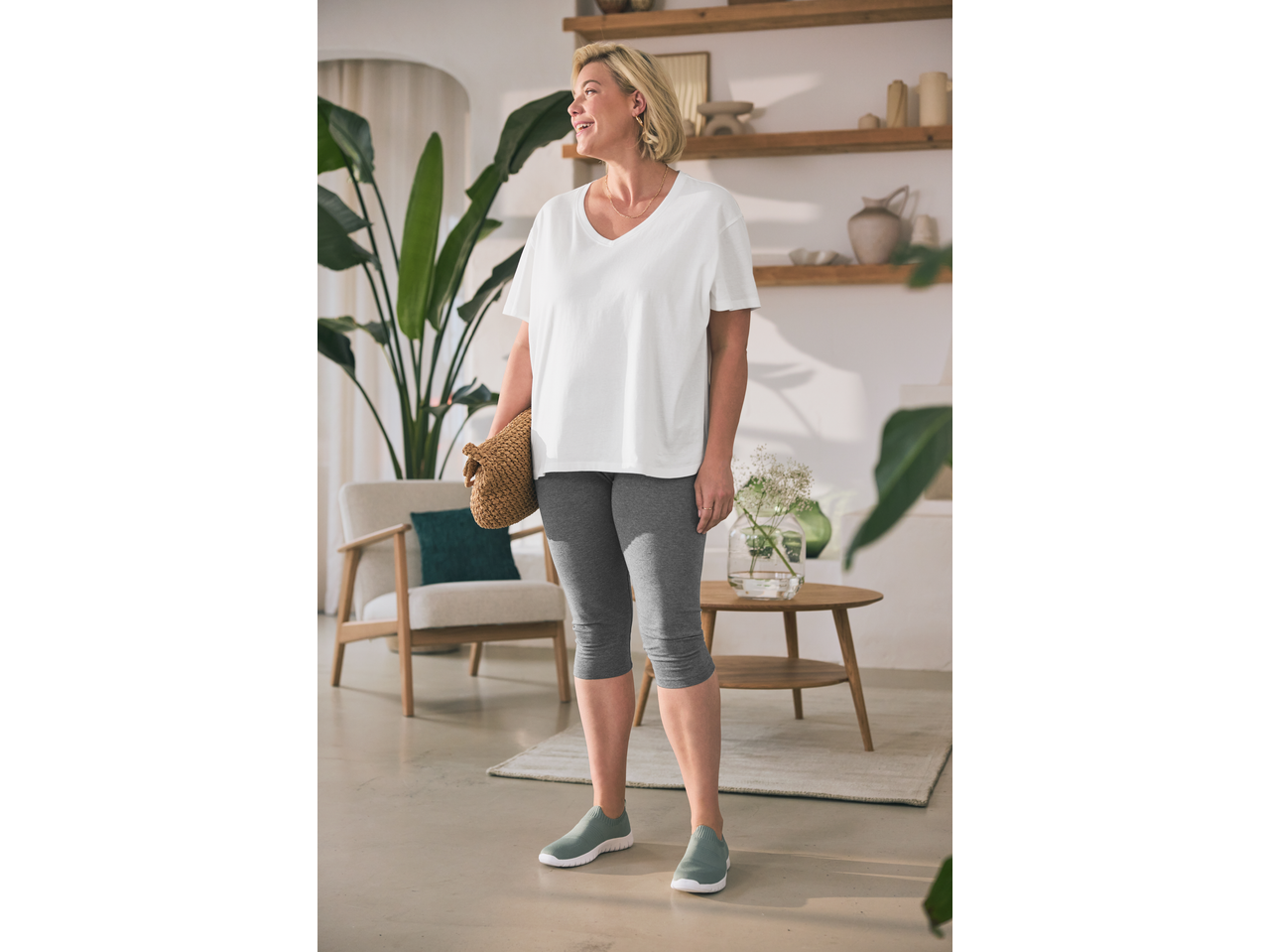 Γυναίκα με λευκό μπλουζάκι, γκρι κολάν ESMARA και πράσινα αθλητικά παπούτσια.