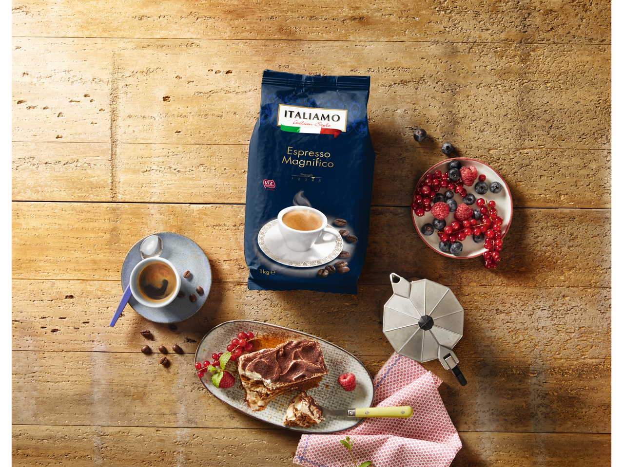 ITALIAMO Espresso Magnifico koffiepakket, espresso, tiramisu en bessen op een houten tafel.