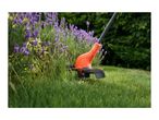 Orange grass trimmer cutting grass next to lavender flowers.