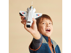 Smiling boy holding a white building block spaceship in his hand.