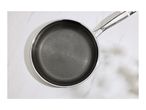 Overhead shot of a frying pan with a honeycomb pattern on its surface, on a white marble background.