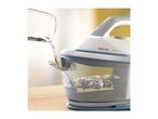 Water being poured into a steam iron with a transparent water tank, showing water splashing.