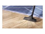 Vacuum cleaner head on a wooden floor, actively cleaning up dirt and debris.