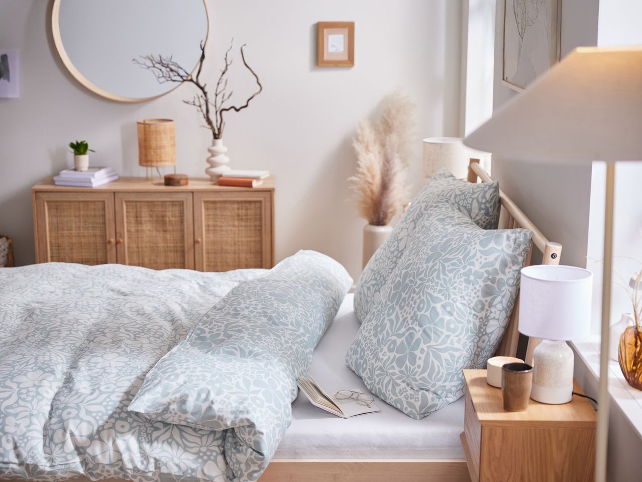 Bedroom with light blue floral bedding, wooden furniture, and decorative accents.