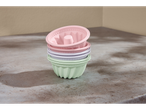 Uma pilha de formas de silicone para assar em cores pastel.