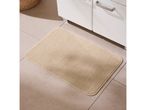 Beige bath mat on tiled floor in front of a white bathroom cabinet.
