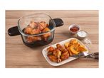 Crispy chicken wings and potato wedges served with ketchup and salt on a wooden table.