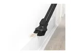 Vacuum cleaner brush attachment cleaning dust and debris from a white baseboard.