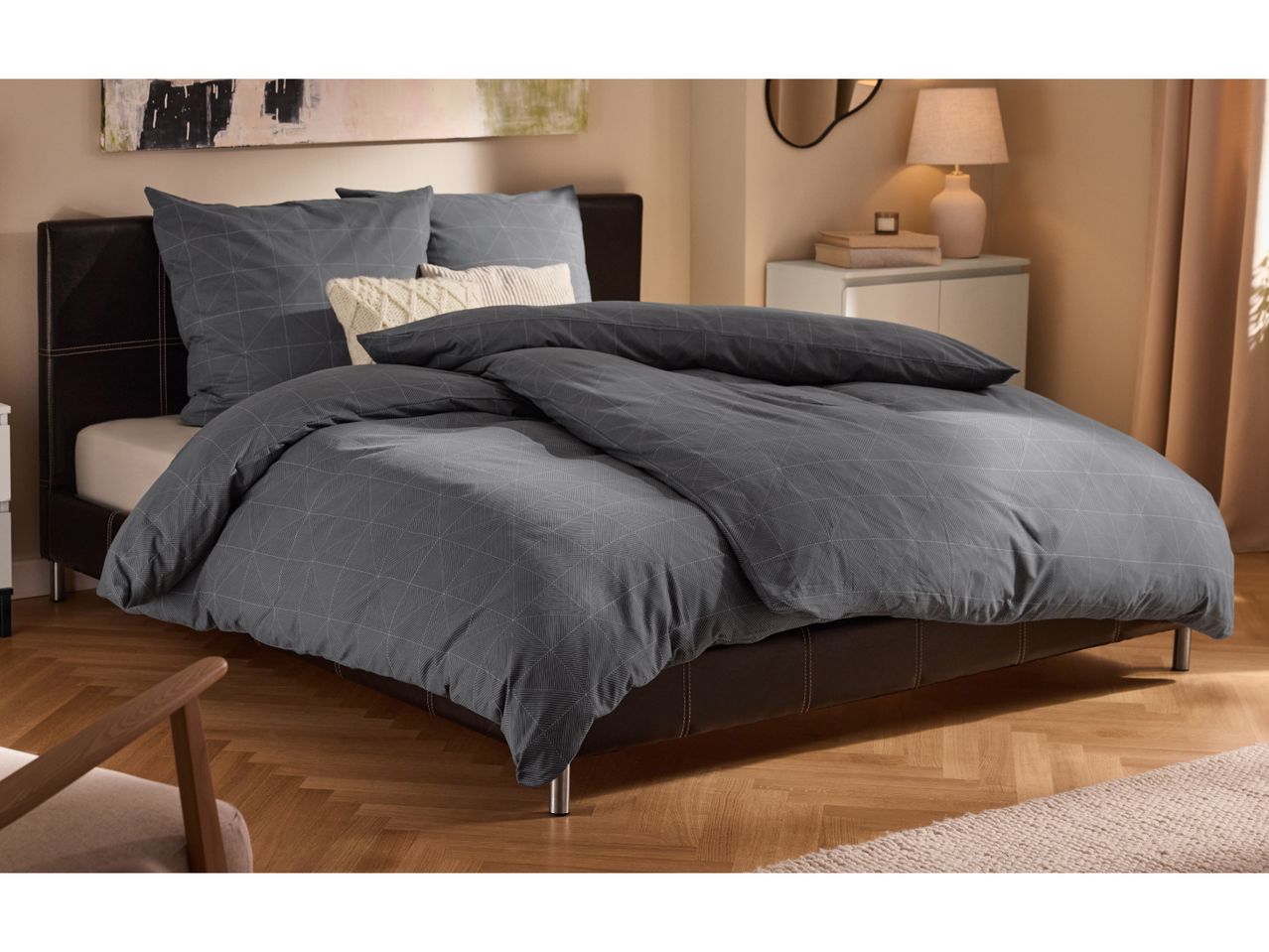 Modern bedroom with a bed featuring dark grey geometric pattern duvet cover and pillows.