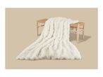Fluffy white faux fur blanket draped over a light wood woven bench