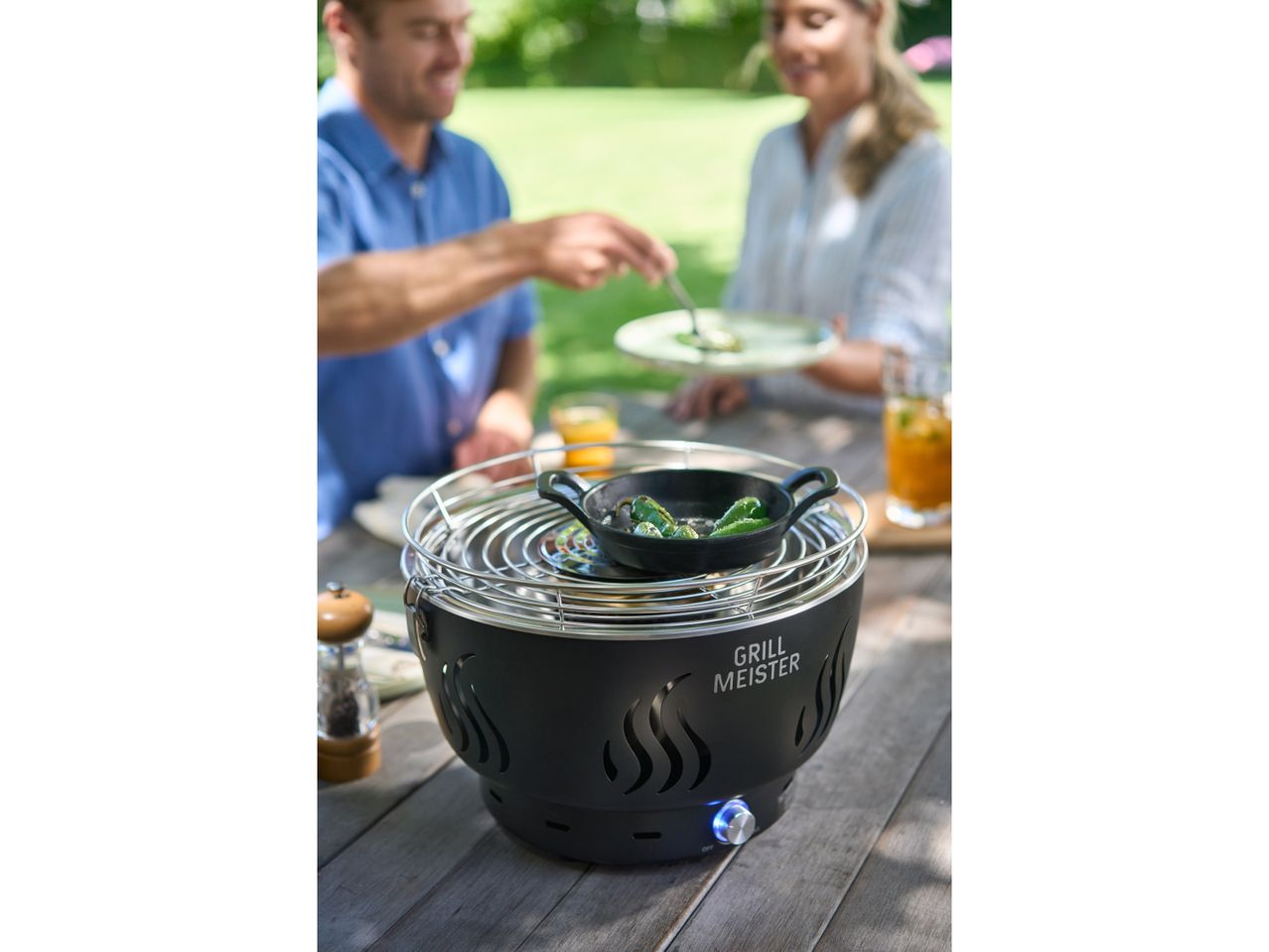 A couple enjoys a meal cooked on a GRILLMEISTER Ventilated Charcoal Barbecue