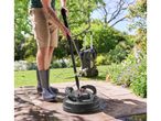 Man in rubber boots cleaning a patio with a pressure washer and surface cleaner.