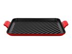 Red cast iron grill pan with a black ridged cooking surface and two handles.