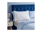 A white pillow with a Silentnight tag on a bed with blue bedding and a blue headboard.