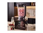 A modern black blender mixing a pink berry smoothie on a kitchen counter.