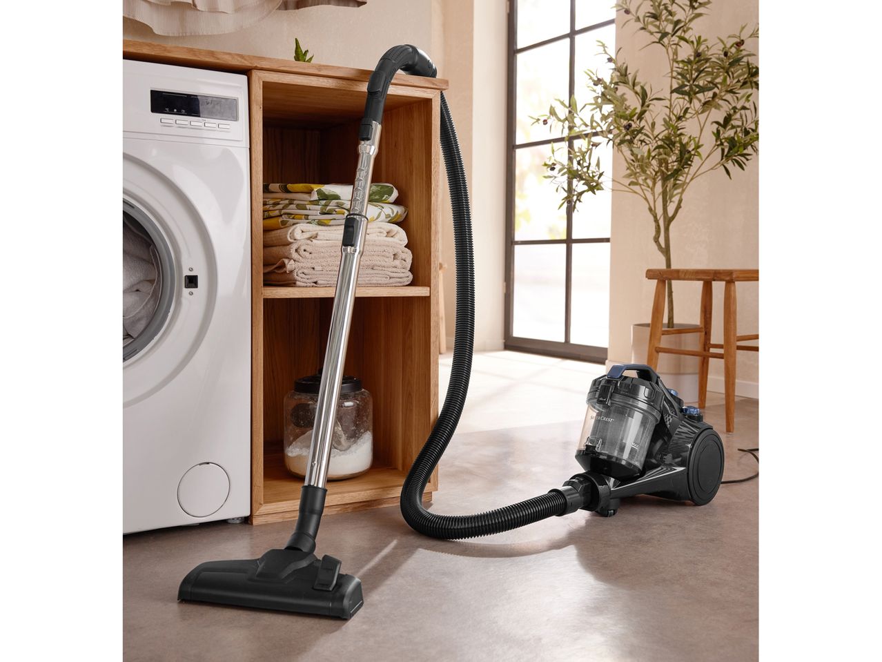 A vacuum cleaner with a washing machine and wooden shelving in a laundry room.