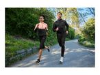 Two people jogging outdoors in athletic jackets and pants on a sunny day.