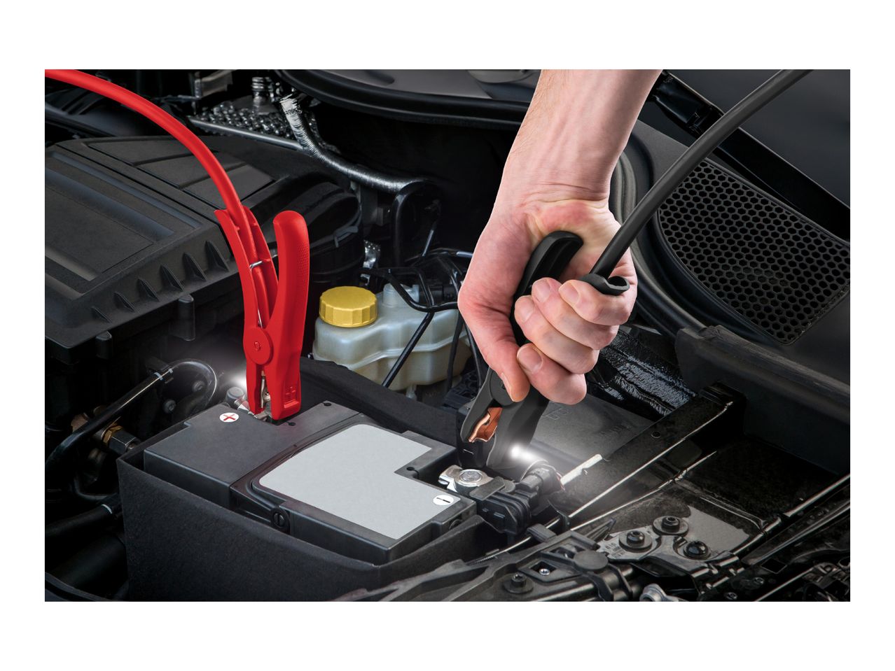 A person jump-starting a car battery with red and black jumper cables.