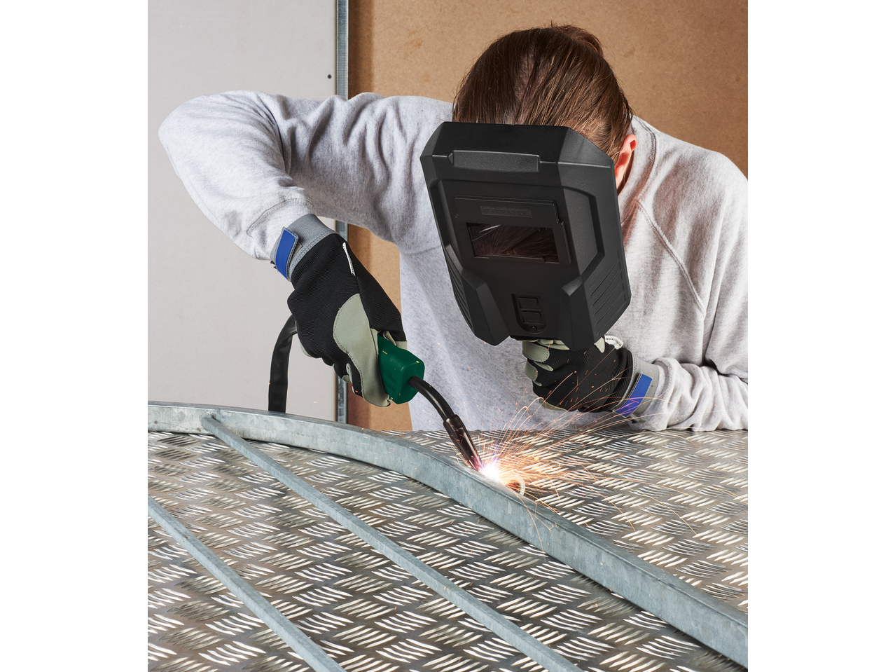 Person welding metal with a PARKSIDE® Inverter Flux Cored Wire Welder, sparks flying.