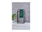 Black towel rack with green towels, a potted plant, and a white bath mat.