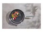 Frying pan with steak and vegetables on a concrete surface.
